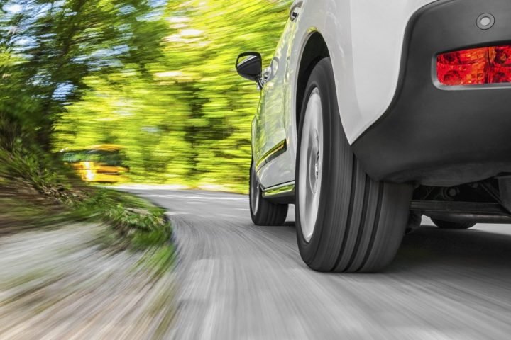 Car driving along a tree-lined country road