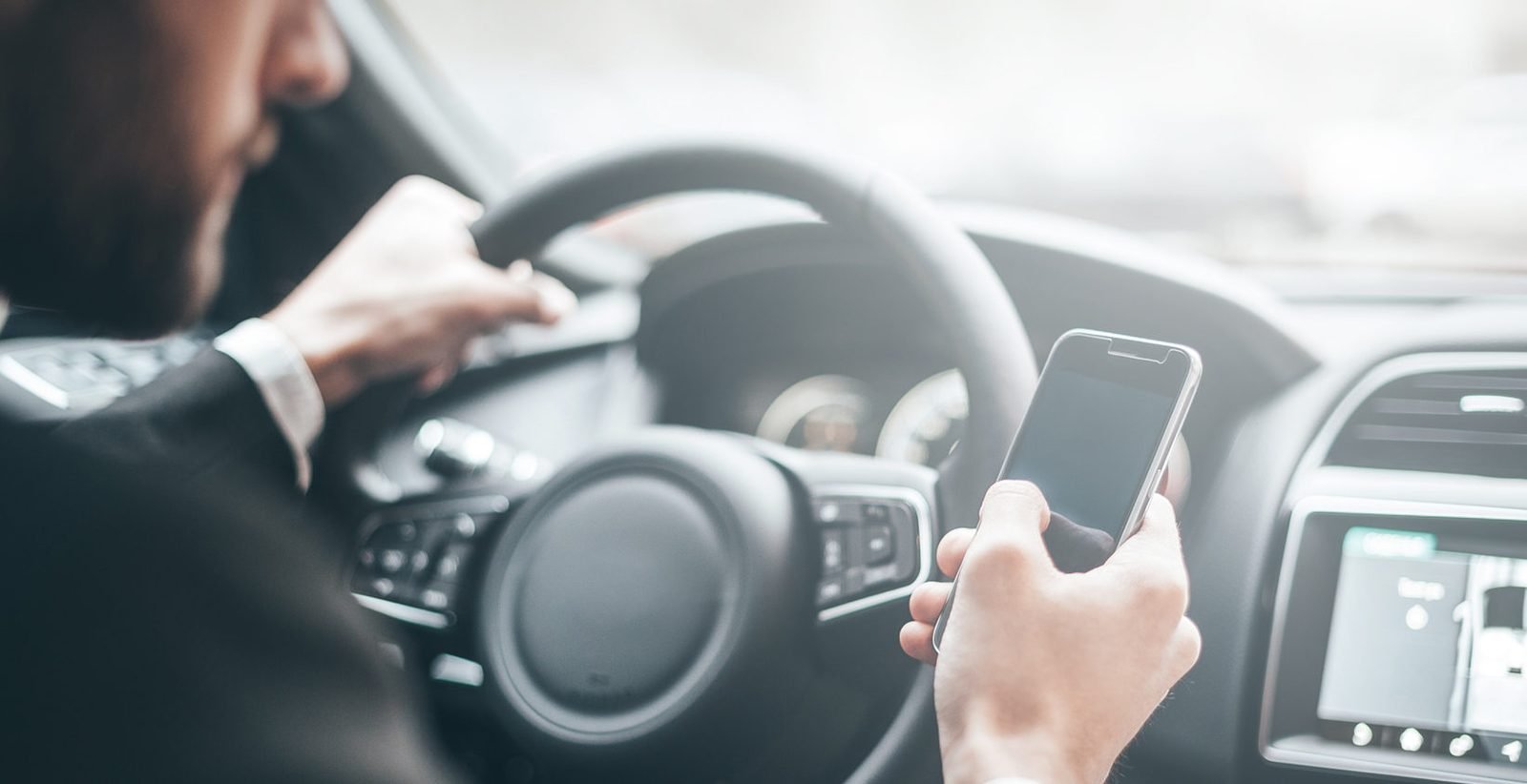 Driver holding a mobile phone at the wheel